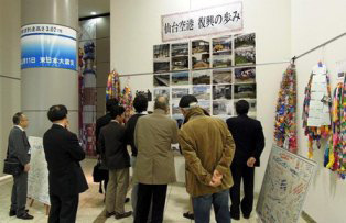 津波の到達地点と併せて仙台空港の復興を見る参加者